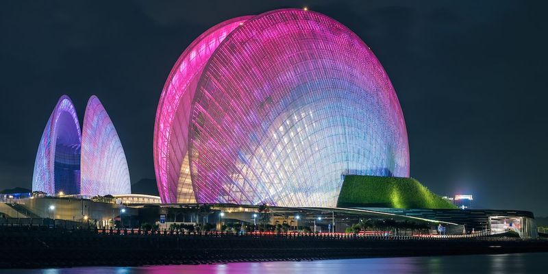A balmy white by day, the Zhuhai Grand Theatre turns purple and pink at night.