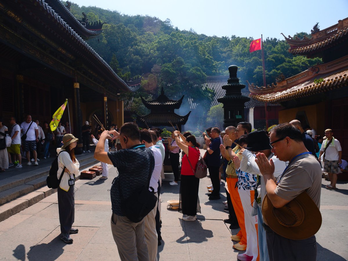 A tour guide leads a tour group in prayer inside Fayu Temple, Mount Putuo Guanyin Island Zhejiang