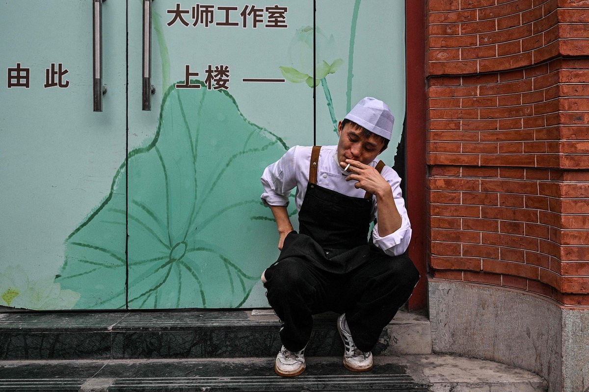 A restaurant worker takes a smoke break outside in Shanghai