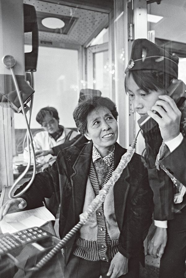 A couple Tianjin women in a phone booth experiencing how to use a telephone. 