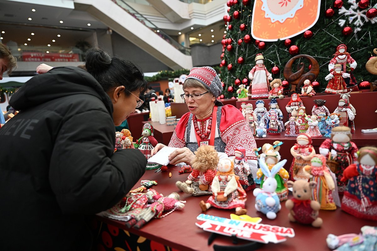 A Chinese customers engages with a Russian artisan at a Russian market in Shenyang