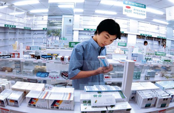 A young Chinese male reads the ingredients on a box of medicine. 