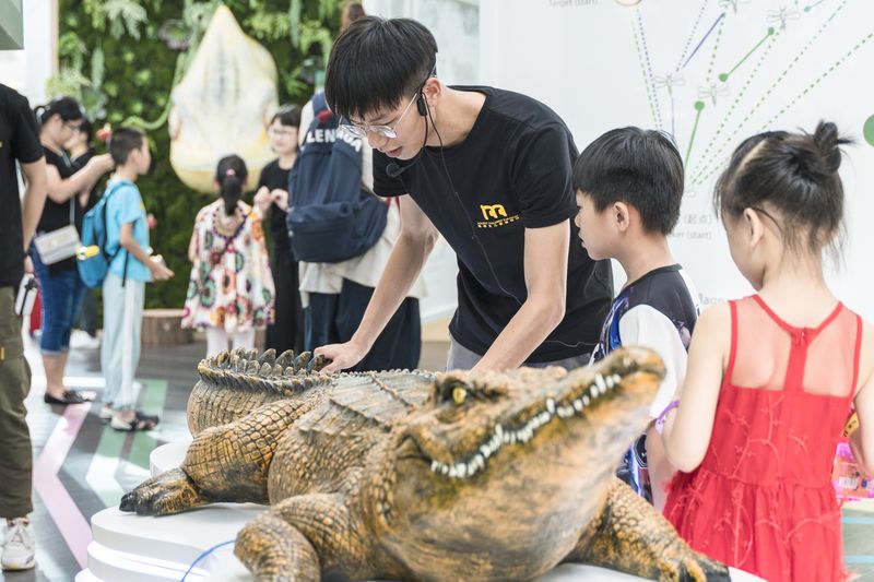 Children investigate a life-size model crocodile at Dotsss children's museum