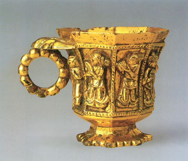 An octagonal, gold-plated cup with emblems of musicians engraved on the side. 