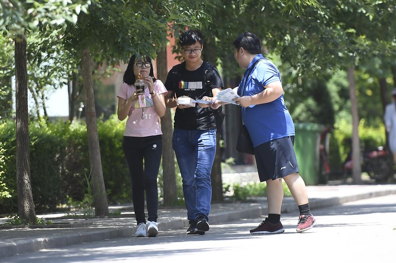 A worker from a sperm bank in Shanxi province hands out promotional material to college students, sperm donors in china
