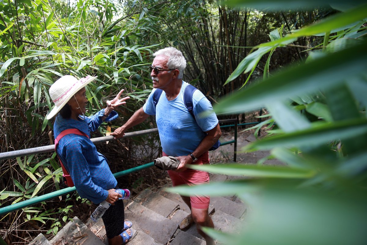 Older Chinese tour guide chats with a foreign tourist in Guilin, Guangxi