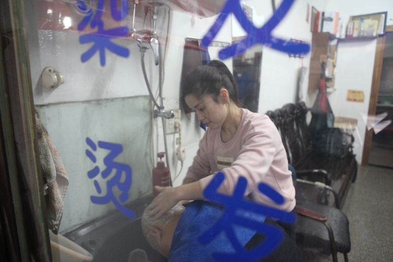 A stylist offers a wash to customers at a hair salon employing deaf staff members in Hangzhou