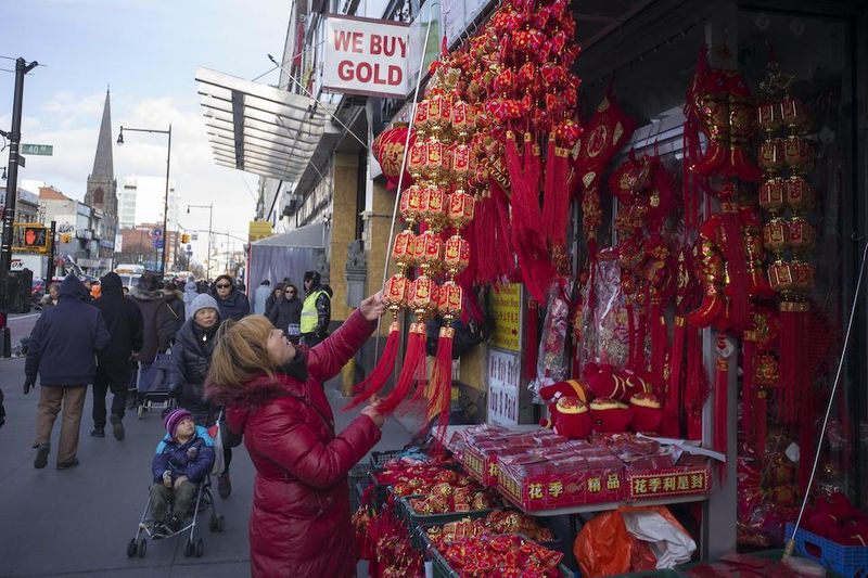 A Chinese woman reorganizes her shop merchandise in Flushing, New York's Chinatown.