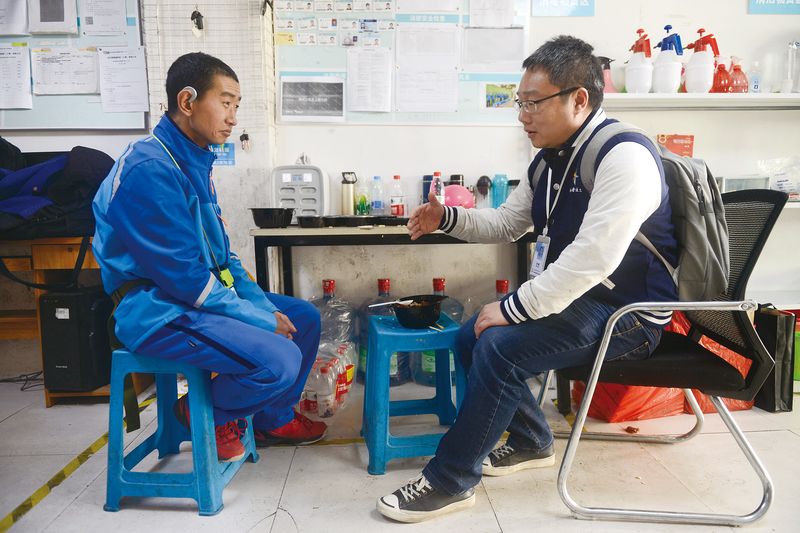 A social worker (right) discusses with a delivery worker and single parent how to provide better care and education to his young daughter in Jiaxing, Zhejiang province