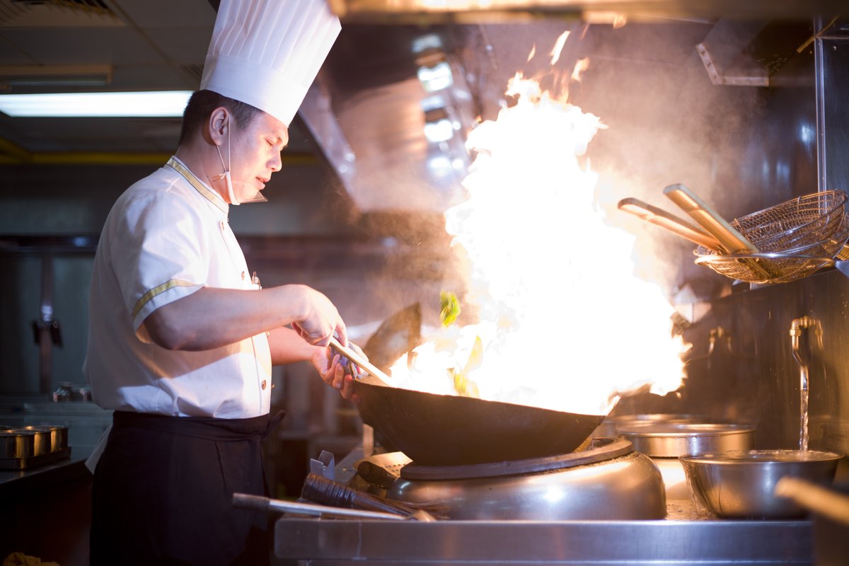 A canteen chef in Guangzhou using a wok to prepare a fresh dish