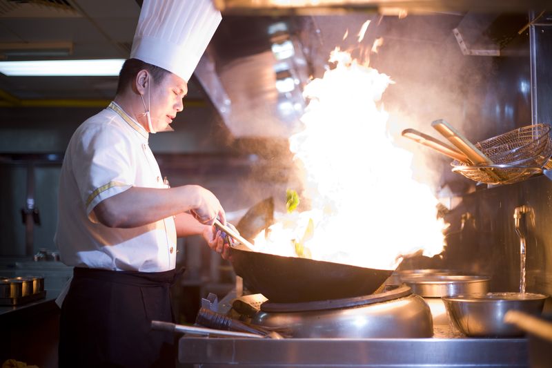 A canteen chef in Guangzhou using a wok to prepare a fresh dish