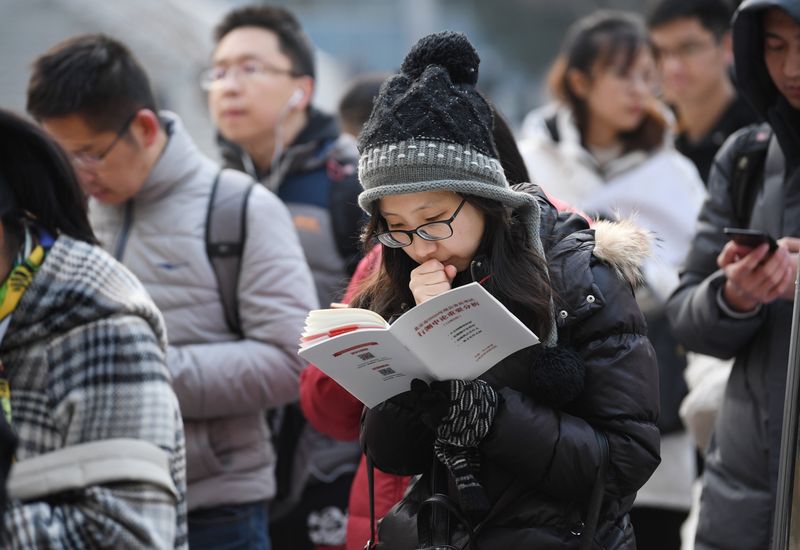 Young Chinese woman preparing for exams and professional qualification tests while in line in the winter, china’s certification craze
