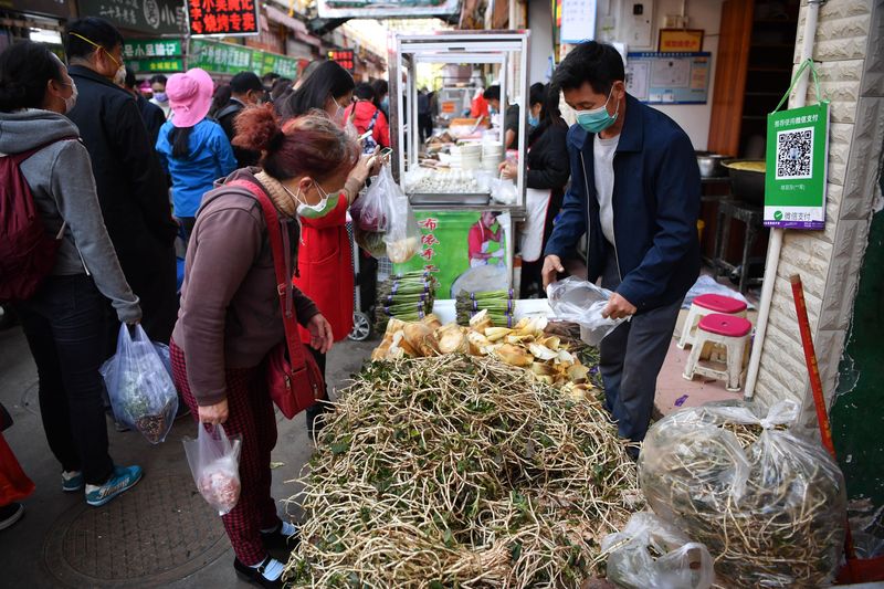 Chinese shoppers at a market in Kunming, Yunnan buying yuxingcao and other Chinese herbs and spices