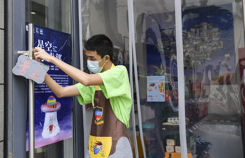 Employee Xiaole opens the doors at the Starry Sky Shop, a Jinan convenience store staffed by people with autism