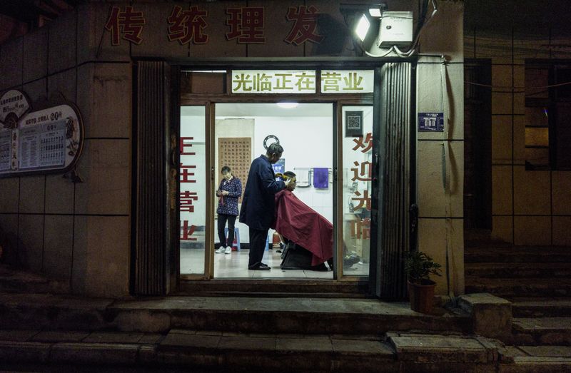 Hairdressers at work in a traditional barbershop in Xiangyang, Hubei province