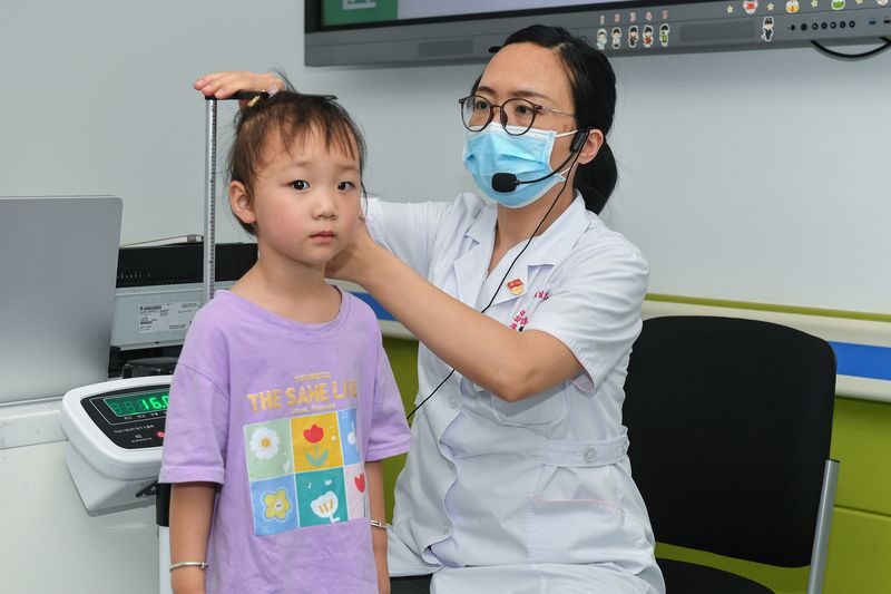 A young girl has her height measured by a doctor