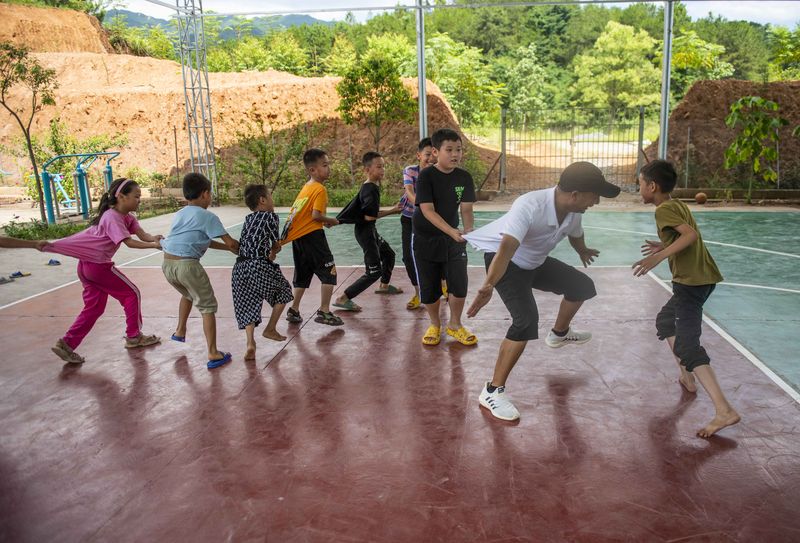 Left-behind children are playing with volunteers during summer vacation