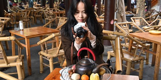 Young Chinese photographer taking photos of her tea