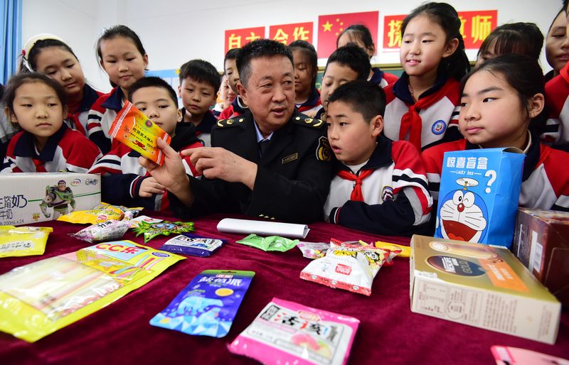 A Chinese government official in Handan city, Hebei province, teaches Chinese elementary school students how to identify fake products and snacks, China’s Consumer Rights Gala