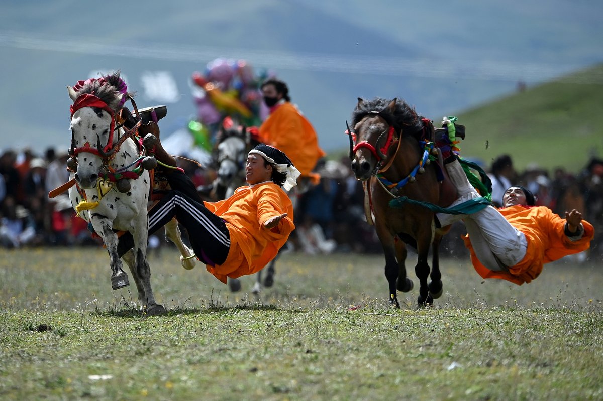 Riders lean sideways and recline with only their legs on the harness to demonstrate their horse-riding skills