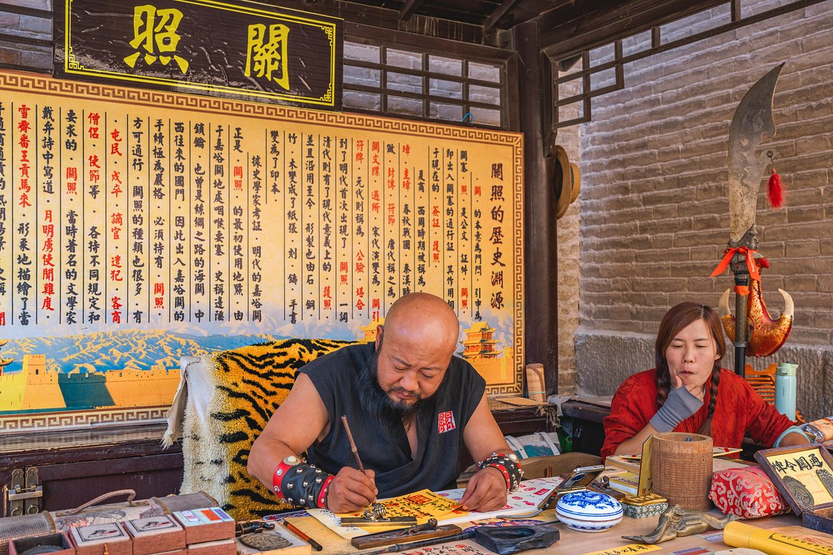A staff member dressed as a commander of Jiayu Pass at the western terminus of the Great Wall issues souvenir travel permits, known as guanzhao (关照) during the Ming dynasty (1368 – 1644), to tourists