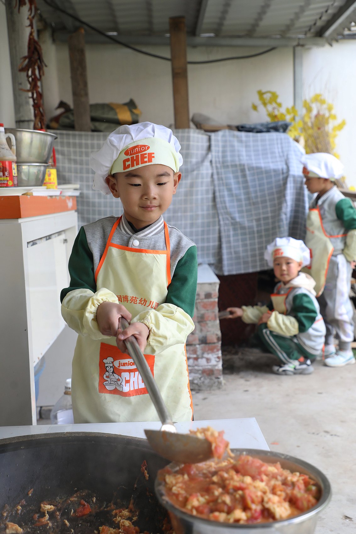 A kindergartener in Tangshan, Hebei, learns how to cook one of China’s most beloved home-style dishes, stir-fried tomatoes with eggs, at school
