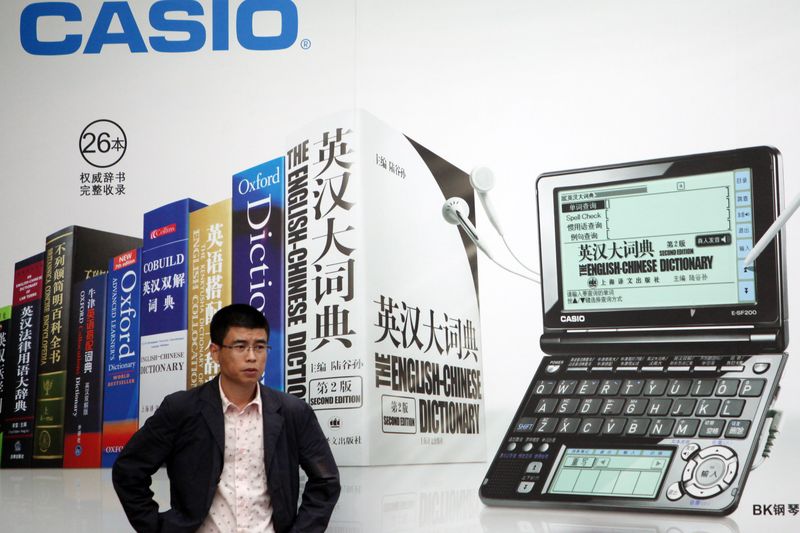 A man stands in front of a Casio electronic dictionary ad in Beijing in 2010