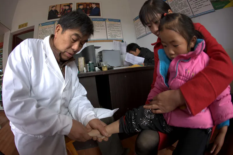 Deng Wanxiang, a village doctor in China, uses a traditional massage method to treat one of his young patients