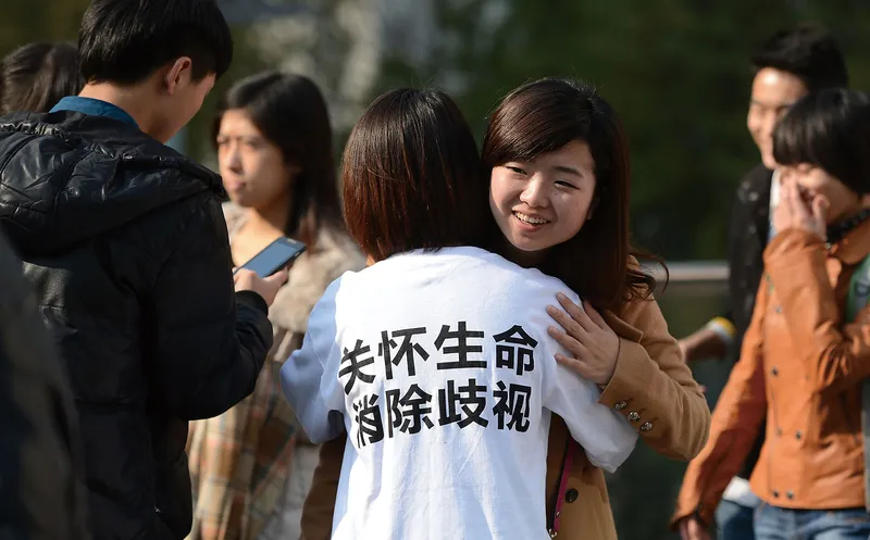 A volunteer promoting HIV awareness hugging a passerby in Chengdu, Sichuan province; her T-shirt reads “Cherish life, eradicate discrimination.”