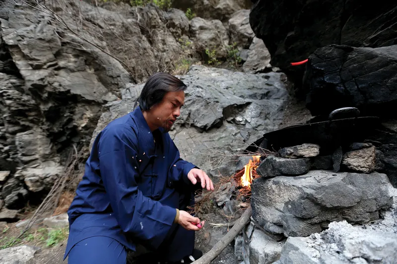 A hermit cooking food outside his cave dwelling on Henan’s Wangwu Mountain