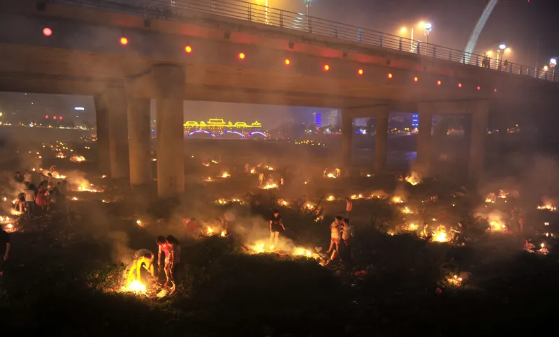 People burn paper next to a bridge for their ancestors