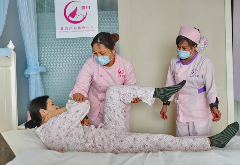 Two yuesao assist a new mother in doing exercises. Yuesao's job involves not only caring for the new infant, but assisting the mother with her recovery