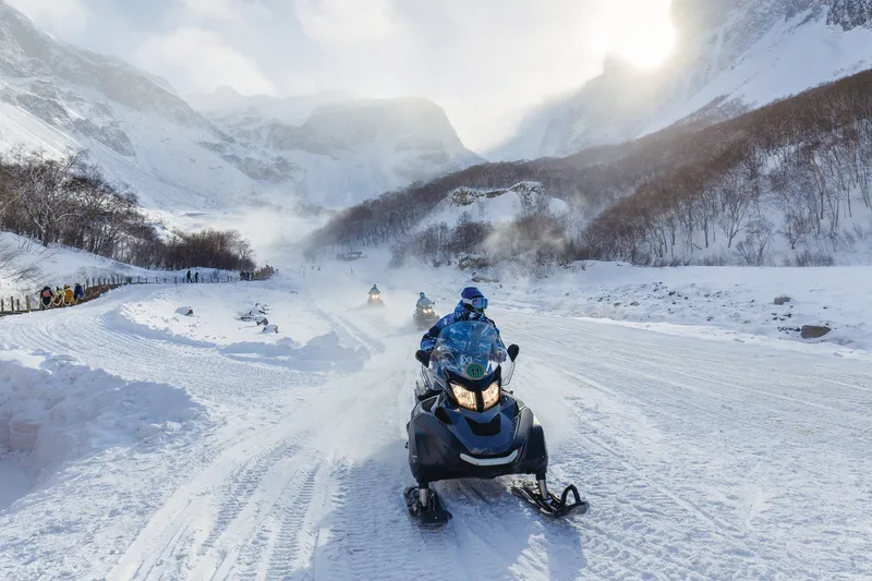 Travelers ride snowmobiles into the mountains