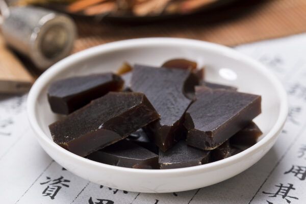 A bowl of donkey hide gelatin sitting on top of calligraphy paper. 
