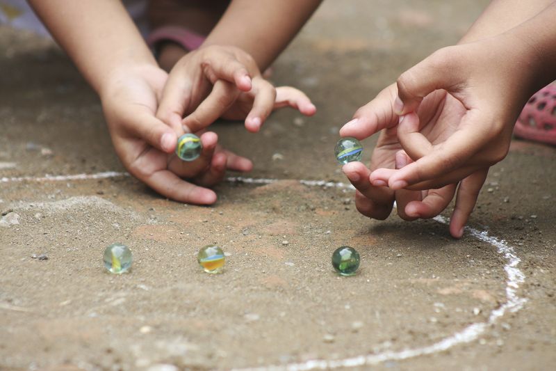 Two children playing with glass marbles