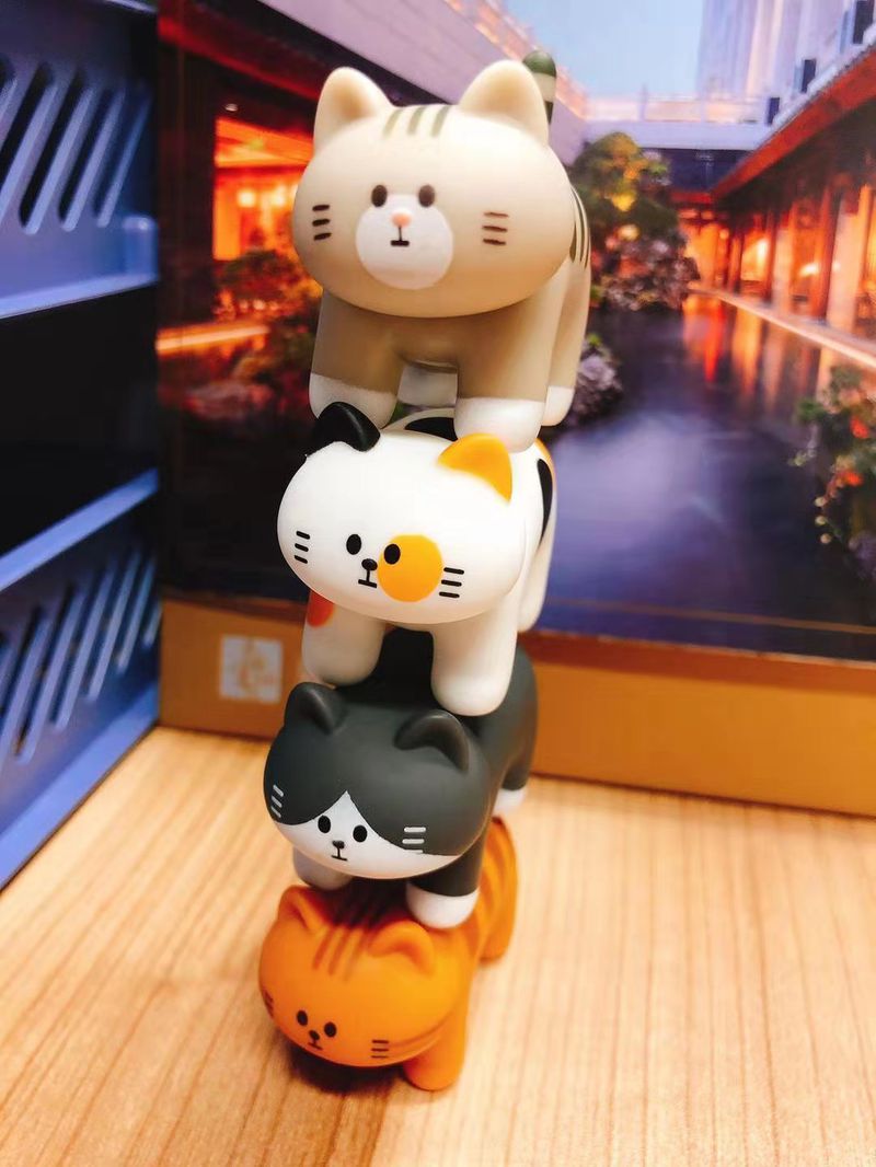 Four designer toy cats stacked on top of each other. 