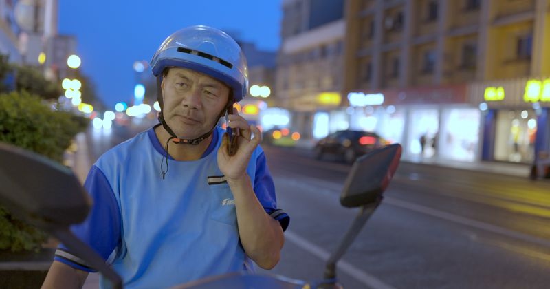 Wang Jibing on a delivery scooter