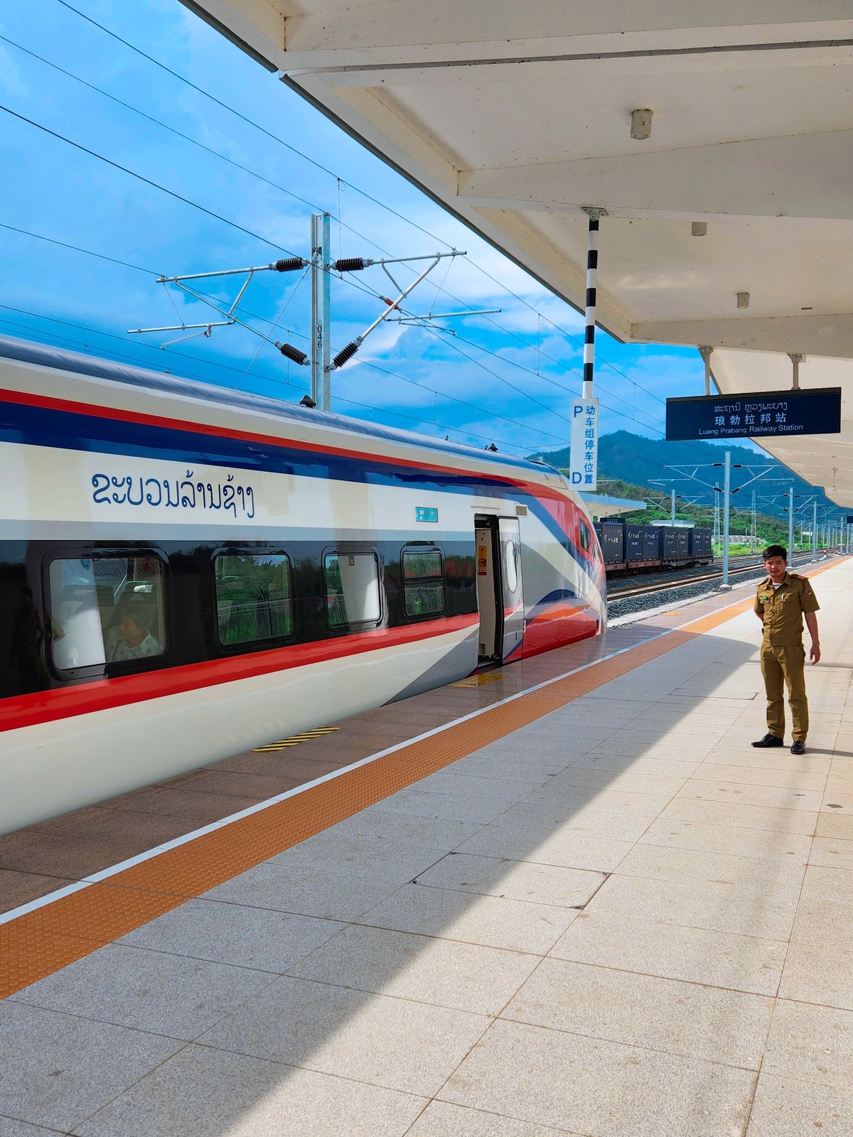 A male Laotian train station employee waits on the platform of Luang Prabang as the laos-china railway arrives