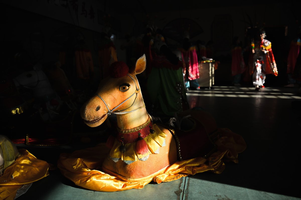 The horse statue is made of bamboo and cloth, brightly decorated, with a silk skirt draped around the bottom