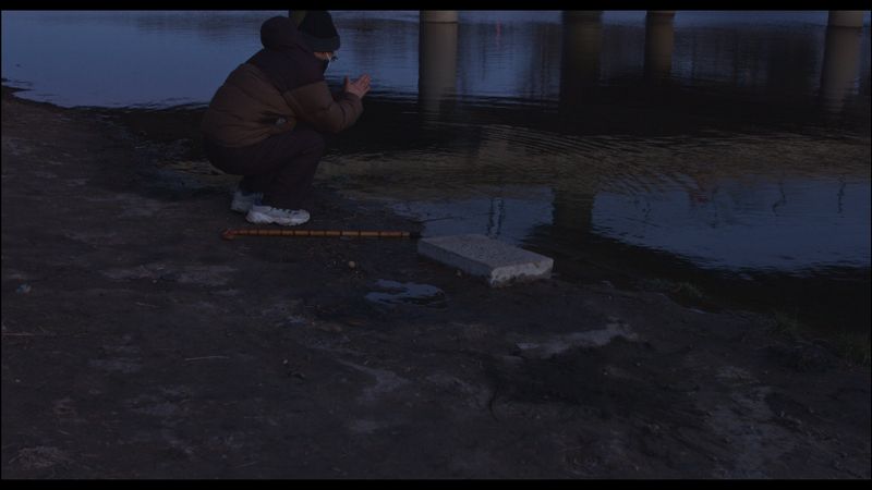 Film screenshot showing a man praying by the pond, ukraine conflict inspires chinese anti-war filmmakers