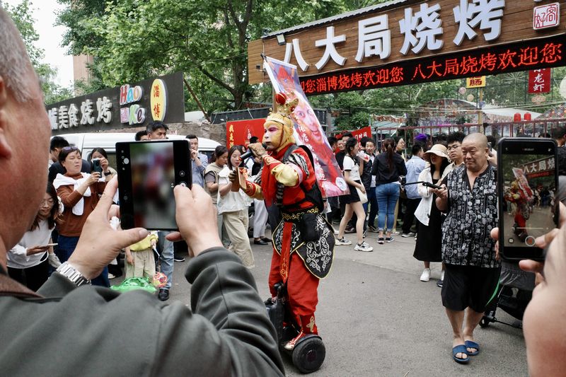 A man dressed in a costume entertaining patrons waiting in line for a barbecue restaurant in Zibo