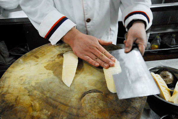 Lay the knife horizontally and slice the bamboo shoots and mushrooms: choose the top part of the bamboo shoots, which is tender. Remove its skin and proceed into inner part. With one hand holding the material in place, slowly work your way to achieve equal slices.