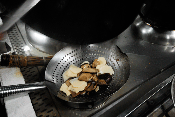 Heat 1,000g water in a wok until boiled. Add the bamboo shoots and mushroom slices. Boil for 30 seconds in order to get rid of the bitterness and remove to drain.