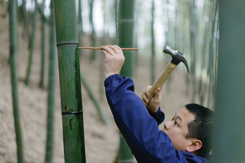 An employee seals the hole in the bamboo with a chopstick