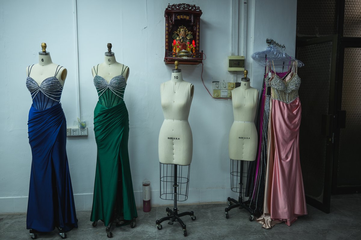 A statue of the God of Money presides over several completed dresses and mannequins in a Guangdong dress factory