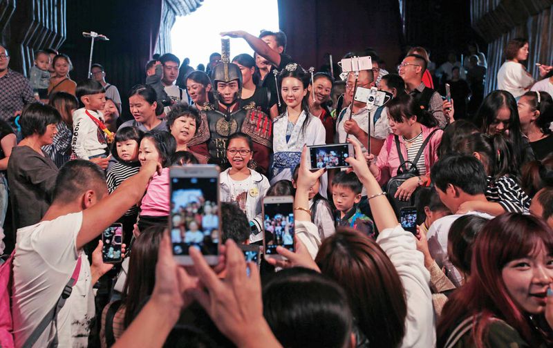 Tourists take photos with staff in costume at the gate of the Palace of Emperor Qin