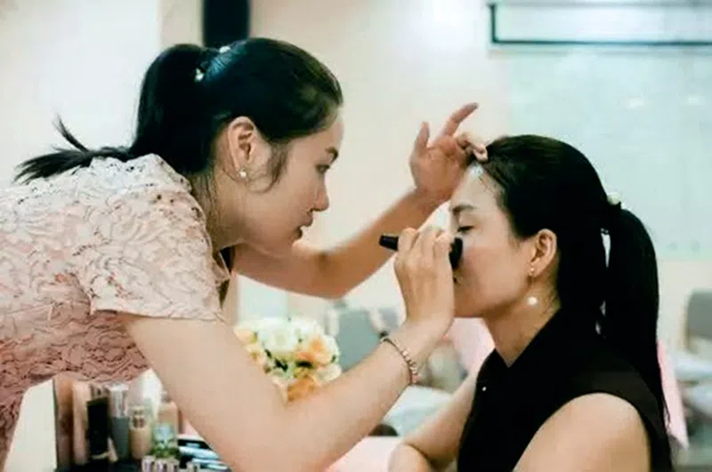 Xiao Jia, one of many inspiring and disabled Chinese women, meticulously applies makeup and blush to a sitting customer.