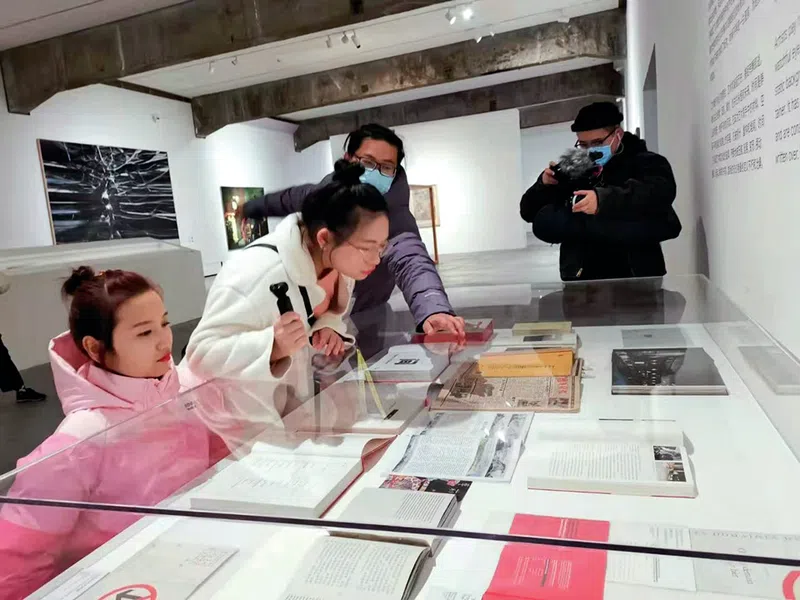 Feminist Peng Yujiao, one of our featured inspiring and disabled Chinese women looks at some booklets within a glass case at the Today Art Museum in Beijing.
