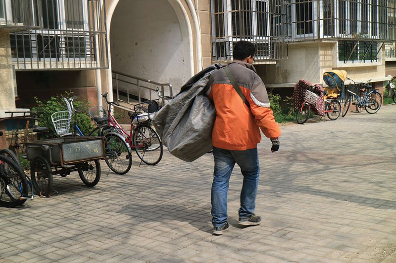 Courier Liu sorts through his delivery bag, arranging packages by floor from highest to lowest, before heading inside 