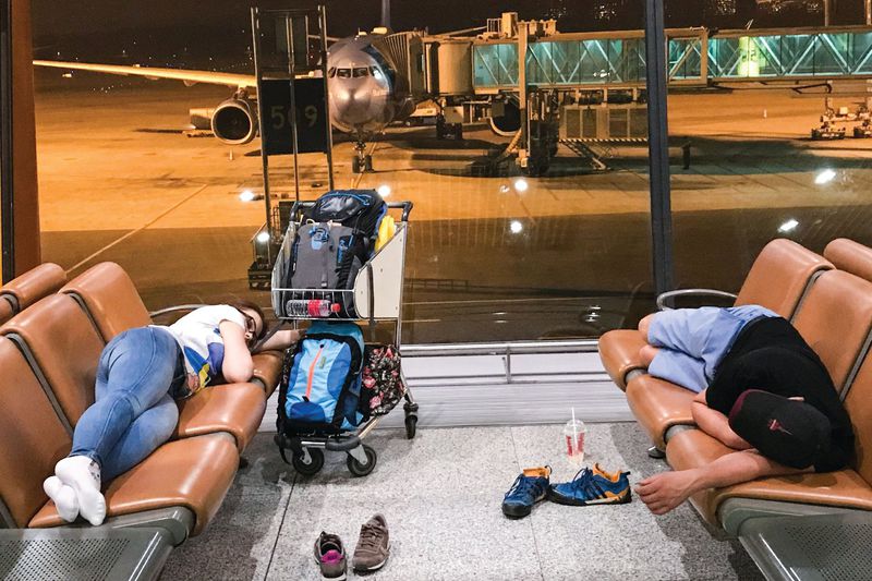 Passengers sleep at the Beijing Capital International Airport. Many passengers choose to stay overnight in order to avoid hotel costs